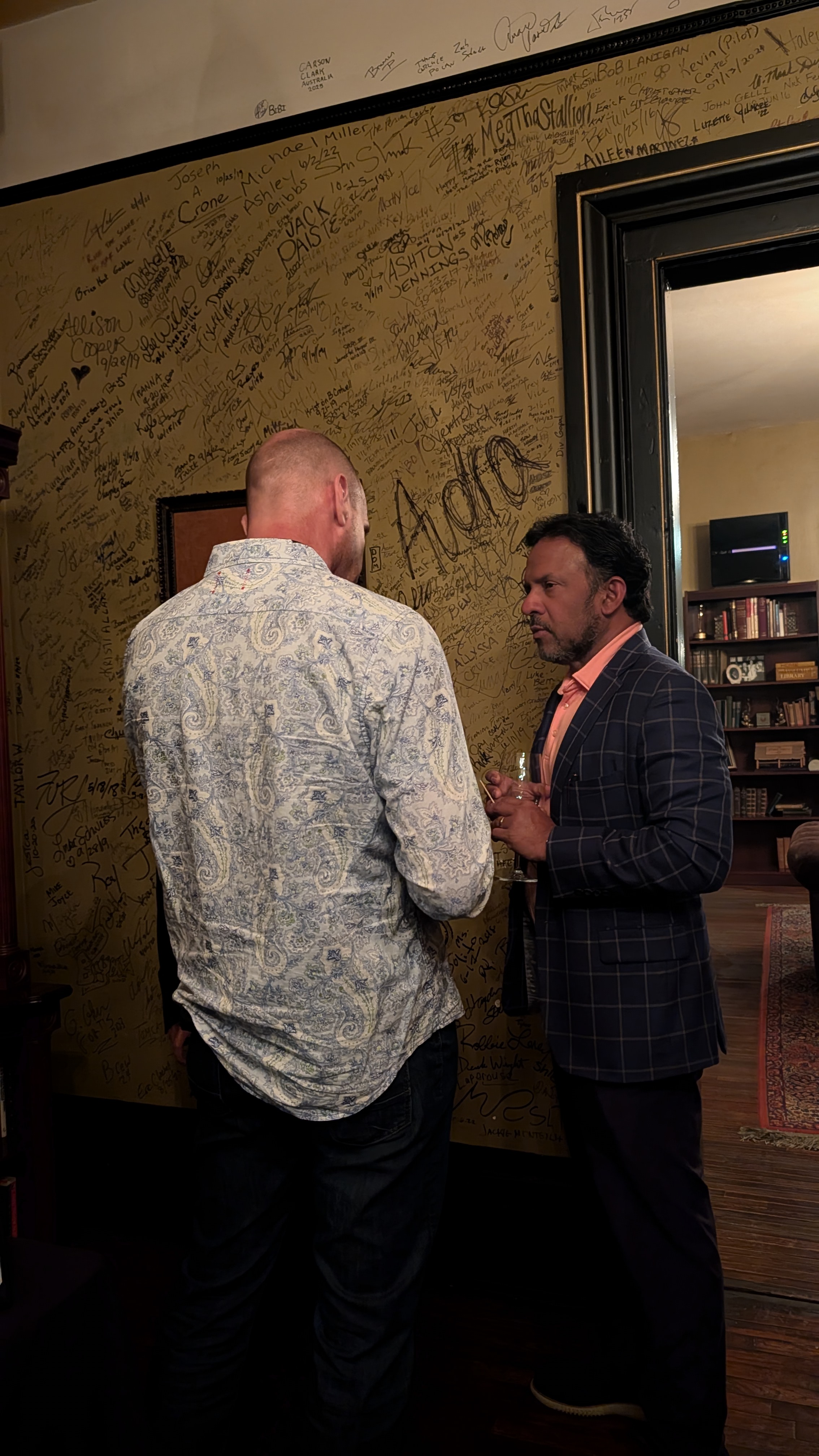 Two founders in conversation by the signature wall
