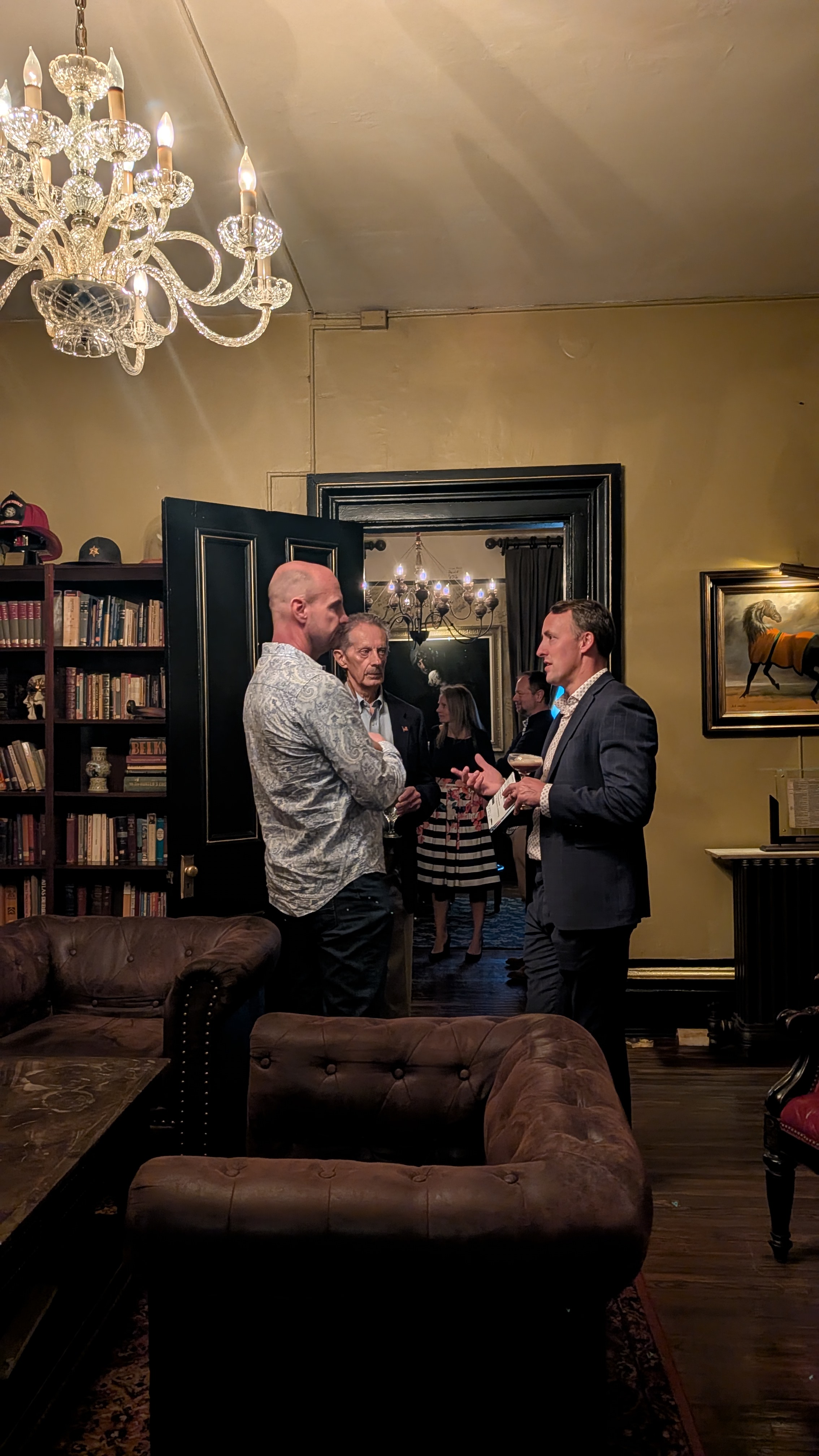 Three founders in conversation beneath the chandelier